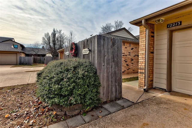 exterior space with a garage, brick siding, and fence