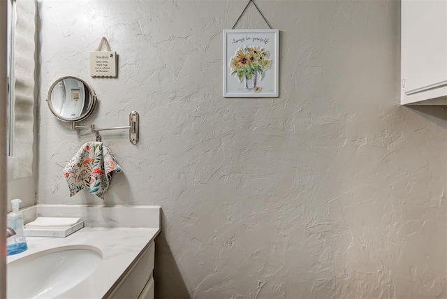 bathroom with a textured wall and vanity