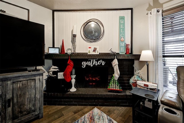 living room with a brick fireplace and wood finished floors