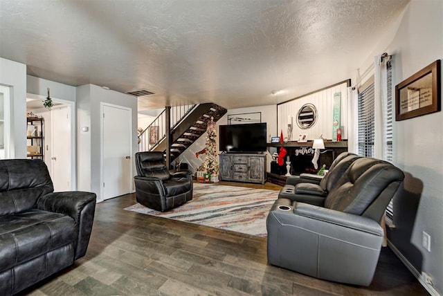 living room featuring visible vents, stairway, a textured ceiling, wood finished floors, and baseboards