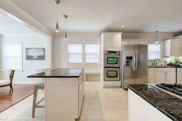 kitchen featuring a sink, appliances with stainless steel finishes, light tile patterned floors, and hanging light fixtures