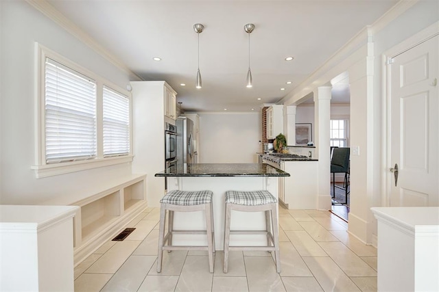 kitchen with visible vents, a center island, a breakfast bar area, ornamental molding, and white cabinets