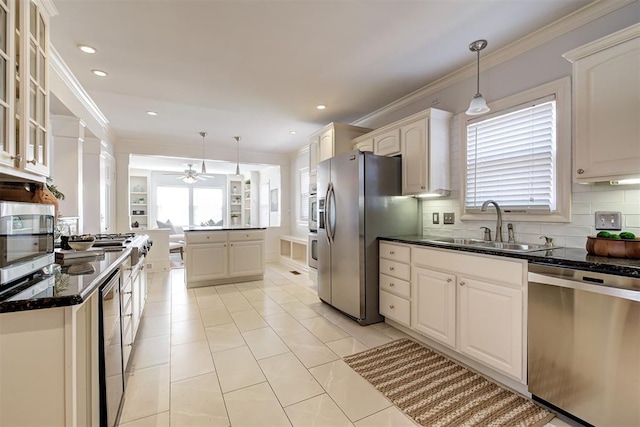 kitchen with a sink, glass insert cabinets, appliances with stainless steel finishes, crown molding, and backsplash