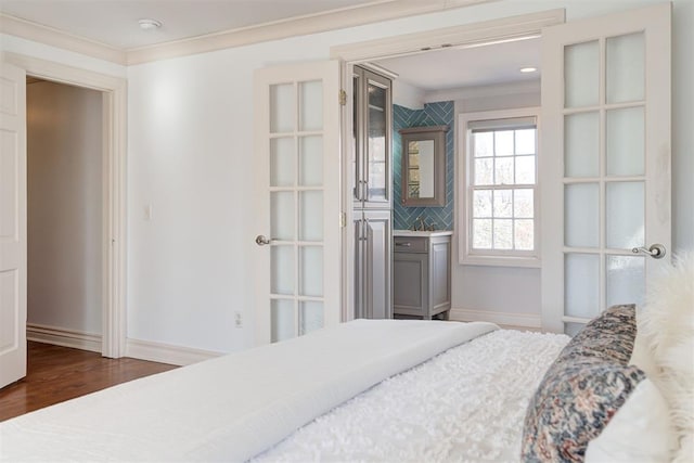 bedroom featuring baseboards, wood finished floors, and ornamental molding