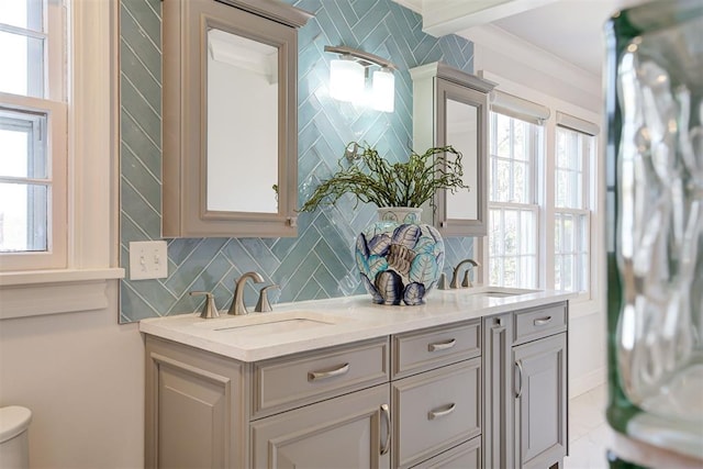 bathroom featuring double vanity, decorative backsplash, toilet, and a sink