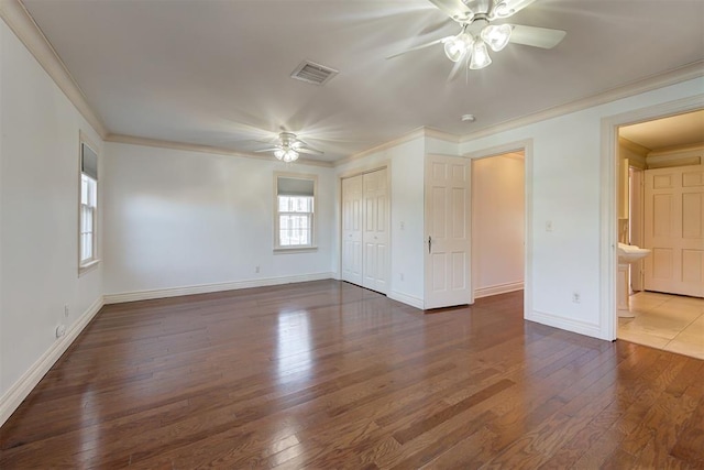 unfurnished bedroom with visible vents, ornamental molding, hardwood / wood-style flooring, baseboards, and ceiling fan