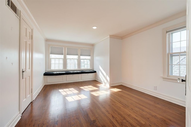 spare room with visible vents, baseboards, dark wood-type flooring, and crown molding