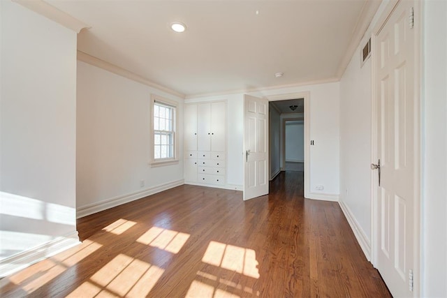 spare room with visible vents, ornamental molding, baseboards, and wood finished floors