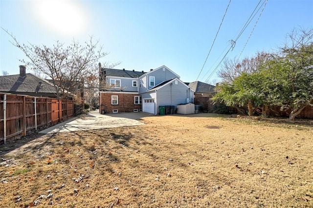 rear view of property featuring a fenced backyard, a garage, and a patio