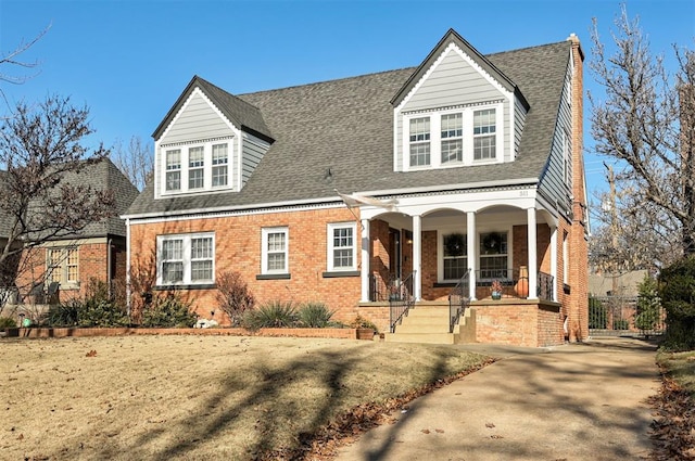 view of front facade with a porch, brick siding, and a shingled roof