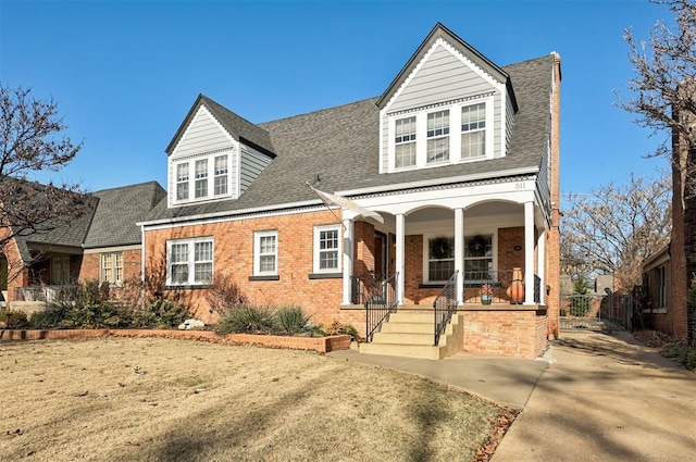 view of front of property featuring brick siding, a porch, and a shingled roof