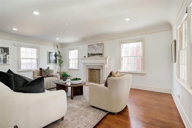 living room featuring recessed lighting, baseboards, a fireplace with flush hearth, and wood finished floors