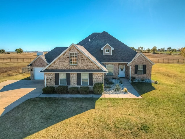 view of front of house with a rural view, a garage, and a front lawn