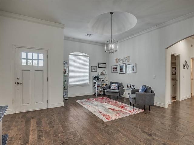 foyer entrance featuring a chandelier, crown molding, and dark wood-type flooring