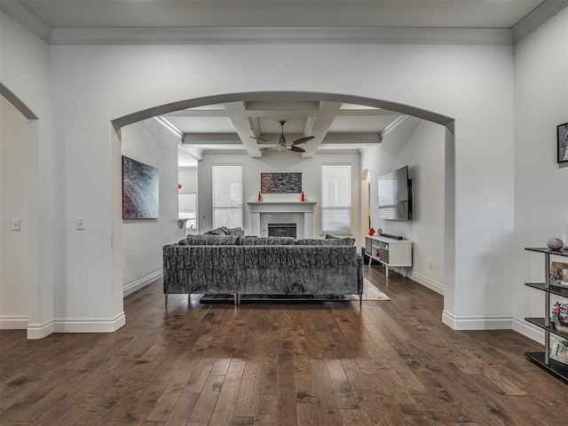 living room with coffered ceiling, dark hardwood / wood-style floors, ceiling fan, ornamental molding, and beamed ceiling