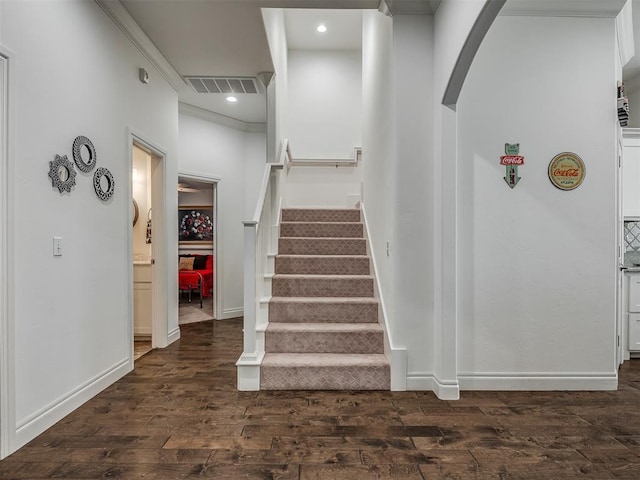 staircase with wood-type flooring and crown molding