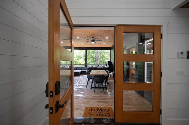 doorway to outside featuring hardwood / wood-style floors, ceiling fan, wooden walls, and wood ceiling