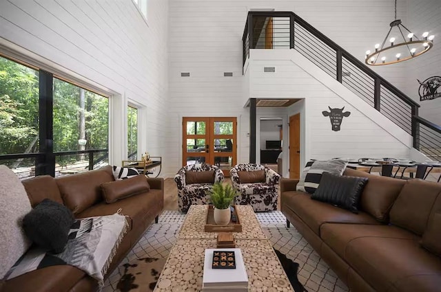 living room with a notable chandelier, a towering ceiling, and french doors