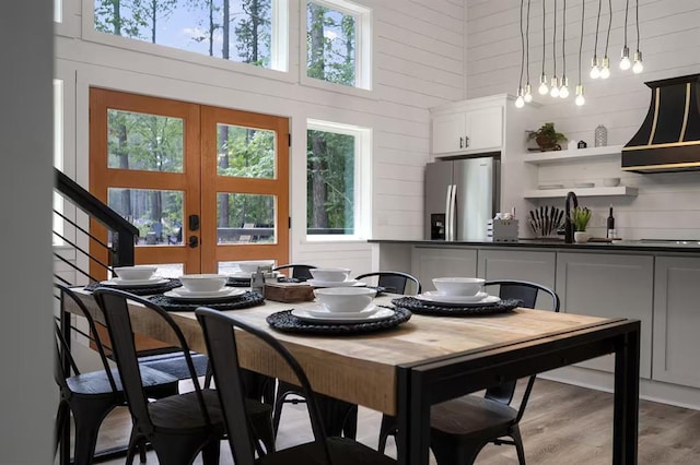 dining room featuring hardwood / wood-style floors, a towering ceiling, french doors, and sink