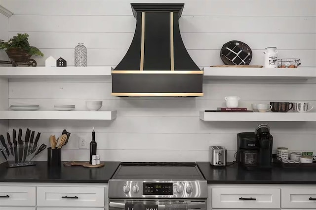 kitchen featuring stainless steel range, white cabinetry, and exhaust hood