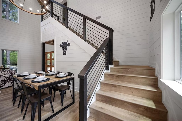 stairs featuring hardwood / wood-style flooring, wooden walls, and a high ceiling