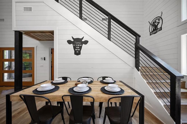 dining area with wood walls and hardwood / wood-style flooring