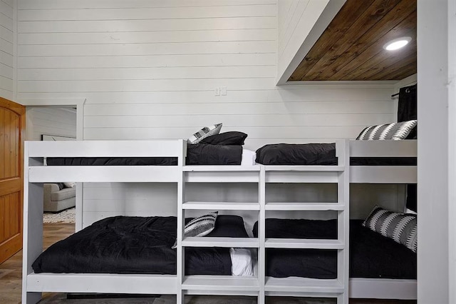 bedroom featuring hardwood / wood-style flooring, wood walls, and wooden ceiling