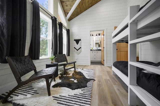 bedroom featuring ensuite bath, hardwood / wood-style flooring, high vaulted ceiling, wooden ceiling, and wood walls