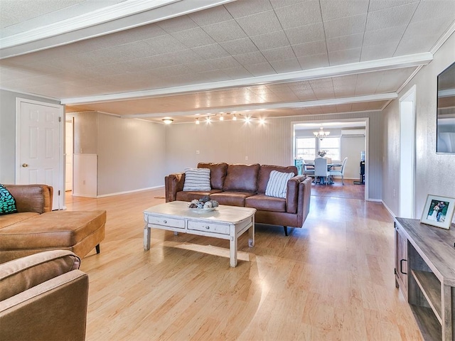 living room featuring light wood-type flooring, crown molding, and a chandelier