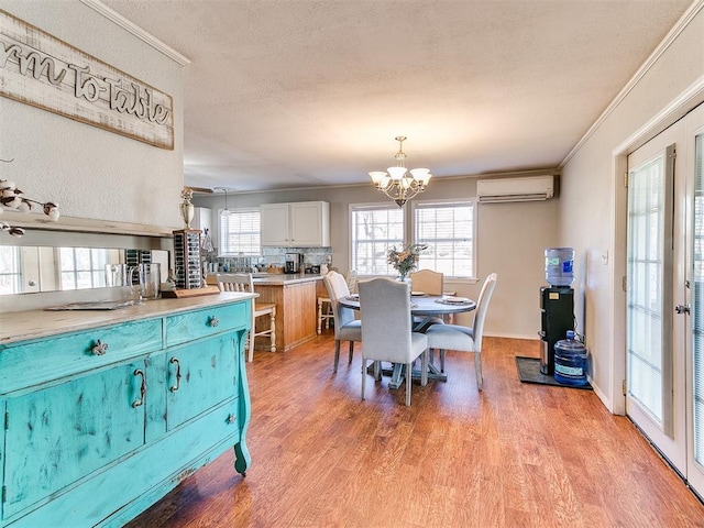 dining space with light hardwood / wood-style flooring, crown molding, a chandelier, and a wall unit AC