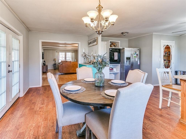 dining space with french doors, ceiling fan with notable chandelier, crown molding, and light hardwood / wood-style floors