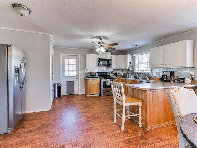 kitchen featuring white cabinetry, kitchen peninsula, stainless steel appliances, pendant lighting, and a breakfast bar