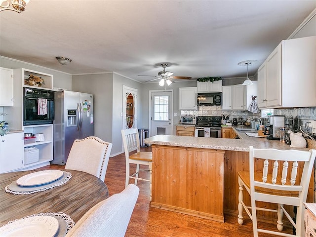 kitchen with ceiling fan, pendant lighting, black appliances, kitchen peninsula, and white cabinetry