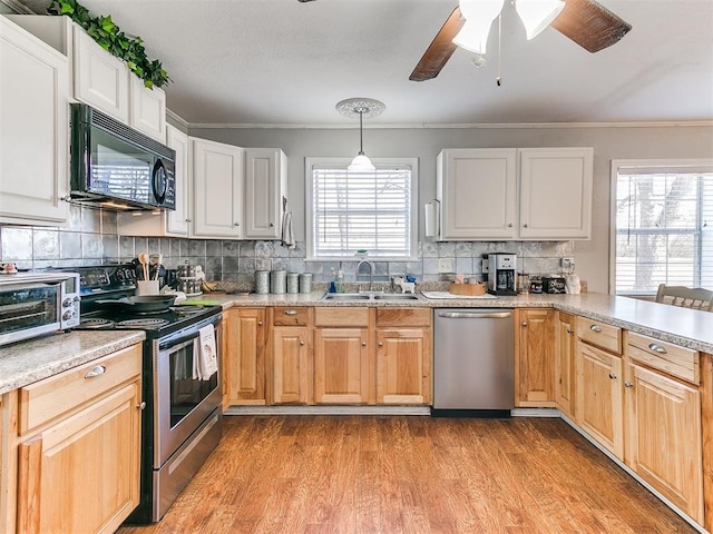 kitchen featuring white cabinets, decorative light fixtures, stainless steel appliances, a healthy amount of sunlight, and sink