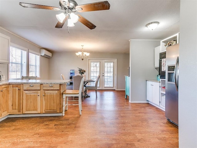 kitchen with black oven, stainless steel refrigerator with ice dispenser, a healthy amount of sunlight, a wall mounted air conditioner, and french doors