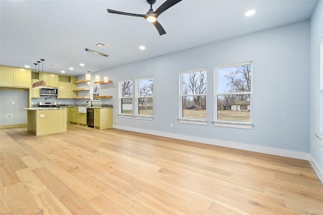 kitchen featuring a center island, hanging light fixtures, light hardwood / wood-style flooring, a kitchen bar, and appliances with stainless steel finishes