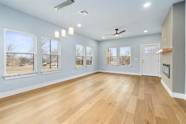 unfurnished living room with light wood-type flooring, heating unit, and ceiling fan