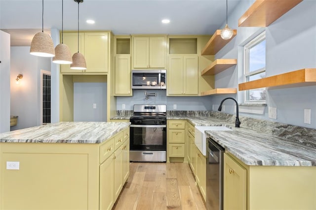 kitchen featuring light stone countertops, stainless steel appliances, light hardwood / wood-style floors, decorative light fixtures, and a kitchen island