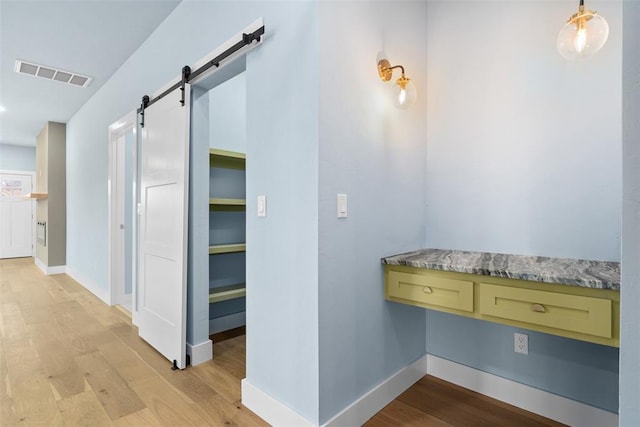 hall with a barn door and light hardwood / wood-style floors