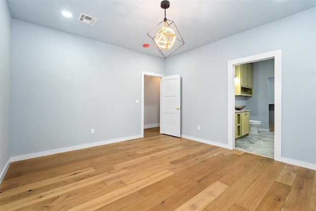 unfurnished bedroom with hardwood / wood-style flooring and ensuite bath