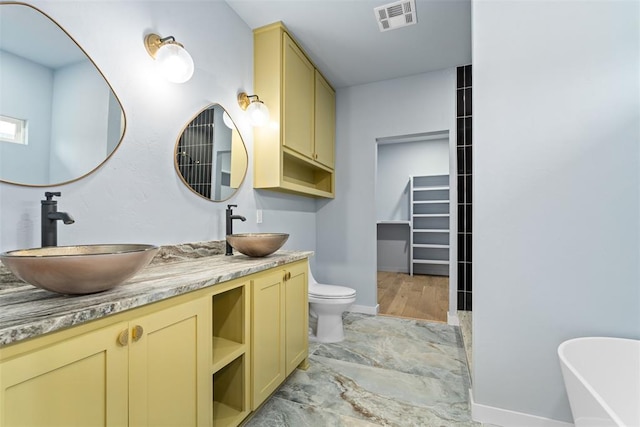 bathroom featuring a washtub, toilet, and vanity