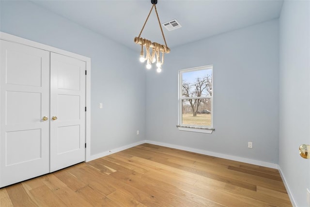 unfurnished room with wood-type flooring and a chandelier