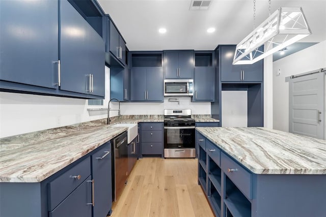 kitchen with appliances with stainless steel finishes, a center island, decorative light fixtures, and blue cabinets