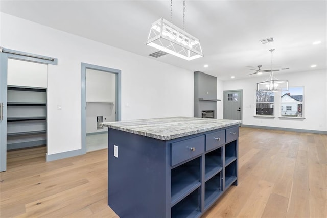 kitchen featuring ceiling fan, a center island, pendant lighting, and light wood-type flooring