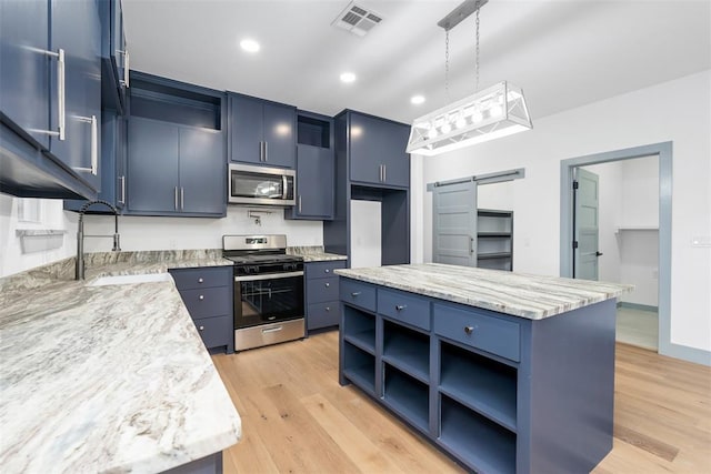 kitchen featuring pendant lighting, a barn door, stainless steel appliances, and blue cabinets