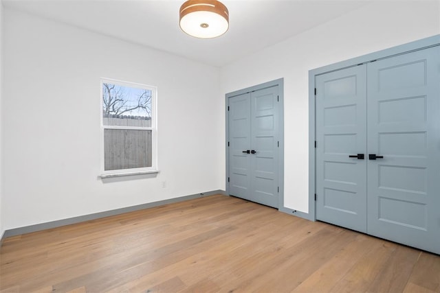 unfurnished bedroom featuring multiple closets and light hardwood / wood-style floors