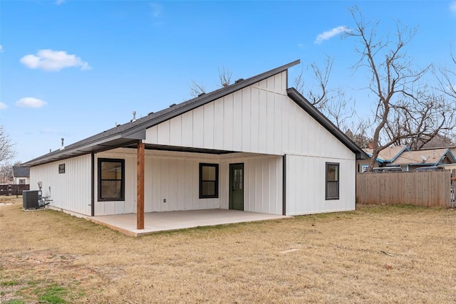 rear view of house with cooling unit, a patio area, and a lawn