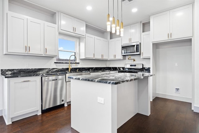 kitchen featuring sink, hanging light fixtures, white cabinets, a kitchen island, and appliances with stainless steel finishes