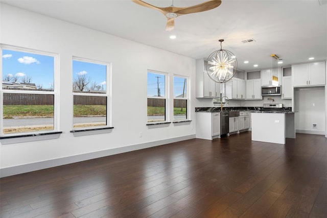 kitchen with white cabinets, a kitchen island, stainless steel appliances, and hanging light fixtures