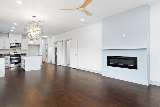 kitchen with white cabinets, pendant lighting, a kitchen island, ceiling fan with notable chandelier, and appliances with stainless steel finishes